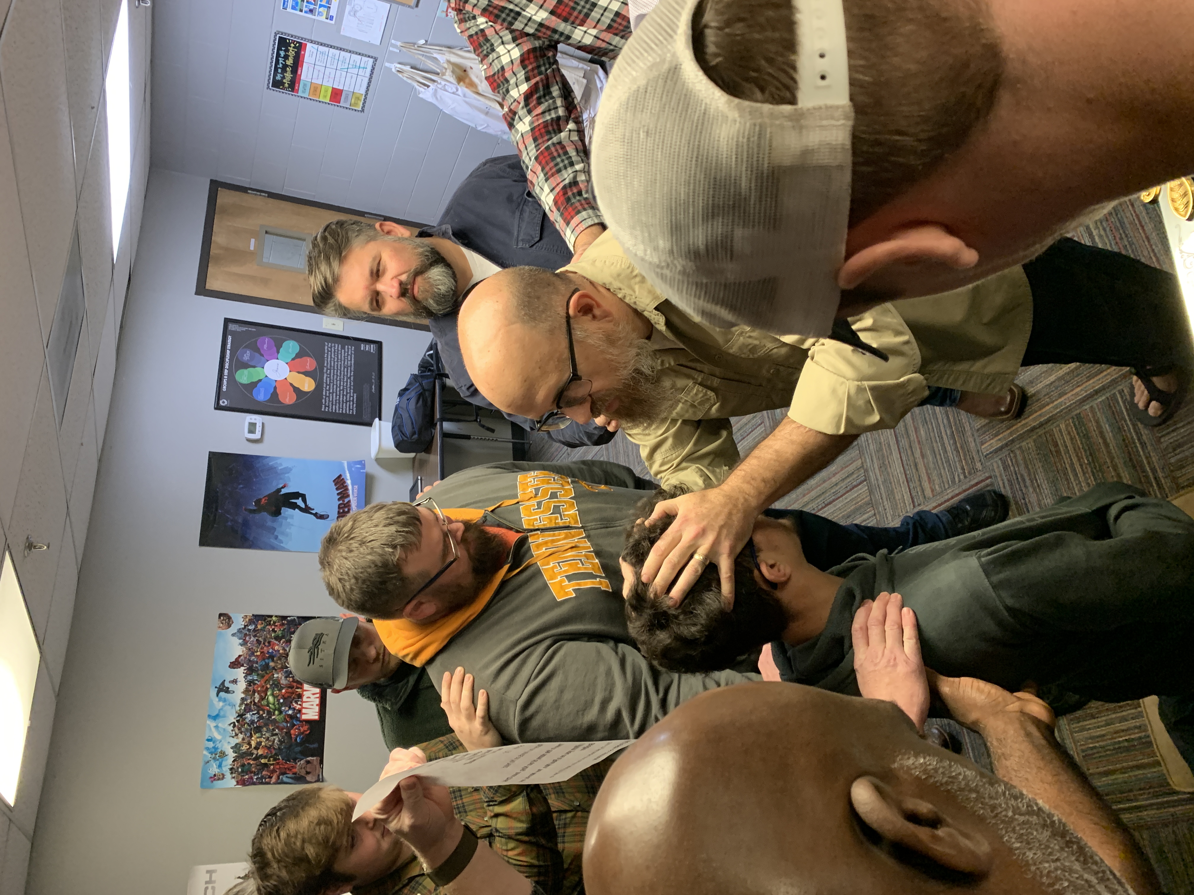Men surrounding and praying over a younger man
